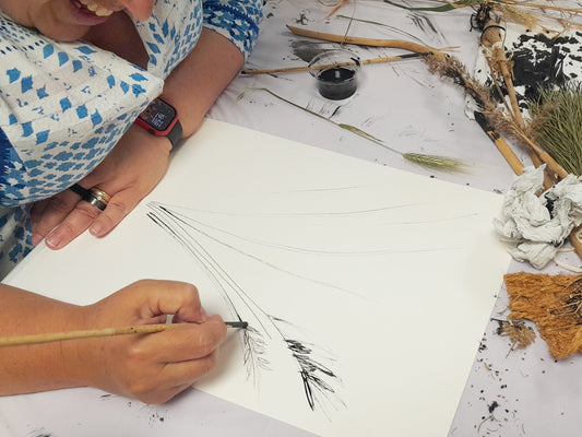 Person drawing on a piece of paper with natural materials