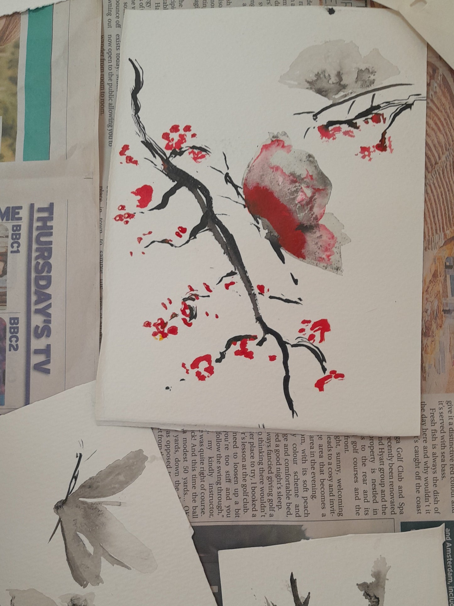 Artistic illustrations of butterflies and branches on newspaper pages.